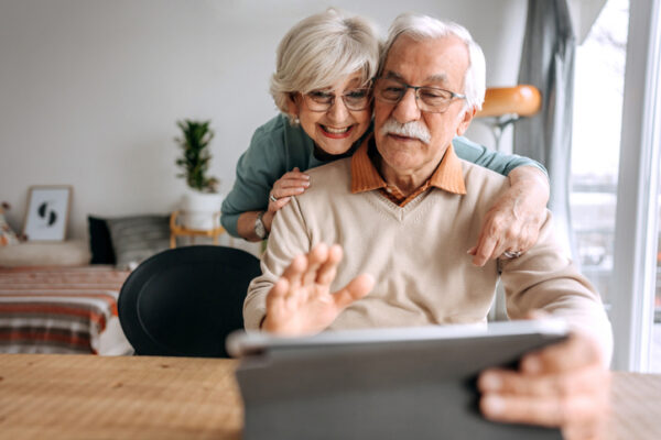 Happy senior couple having video call on a digital tablet at their home